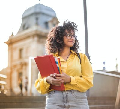 woman in yellow jacket holding books